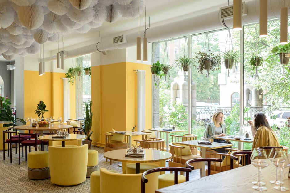Lyst kafélokale med sitteplasser ved store vinduer.