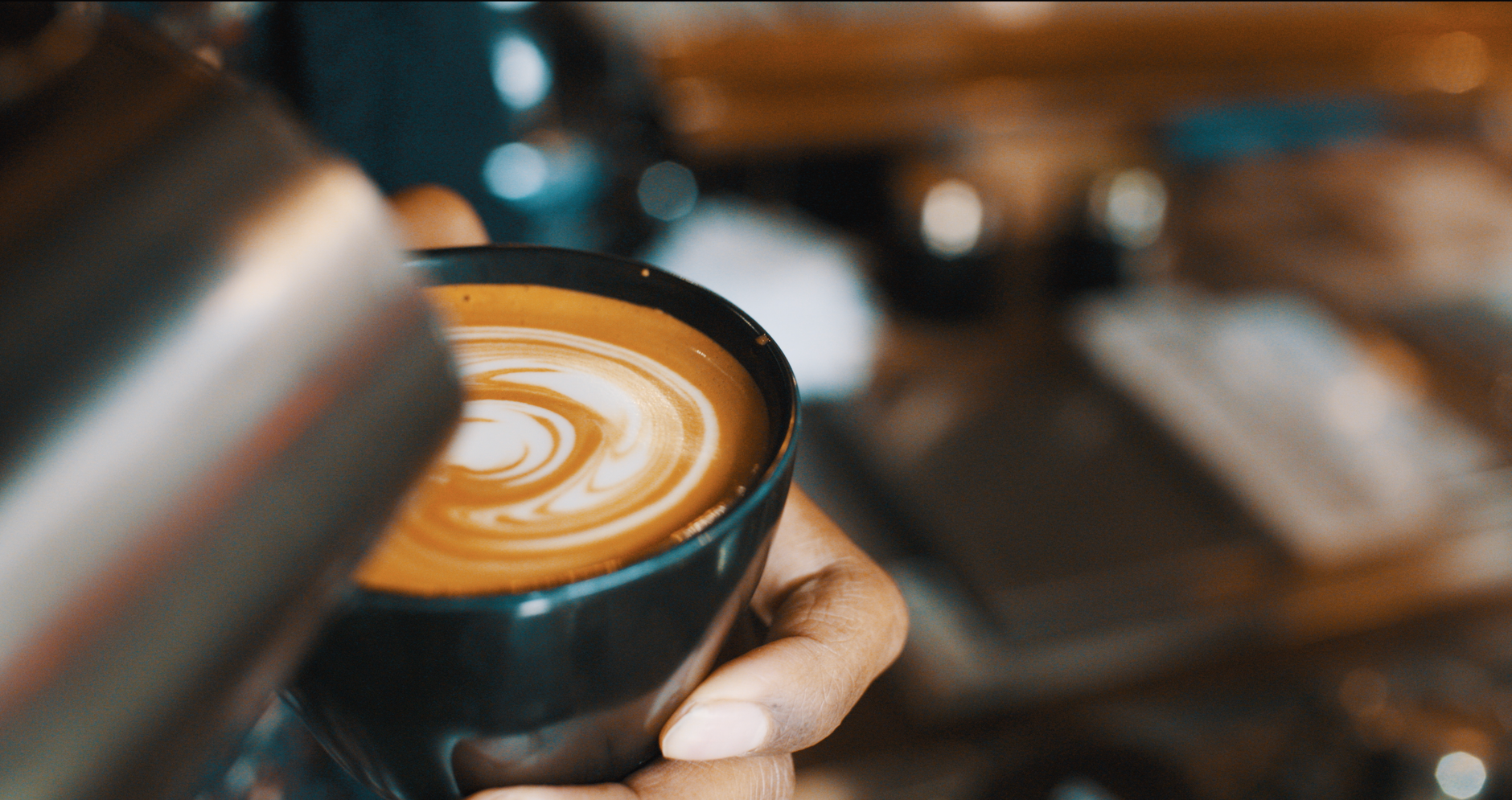 Barista heller melk i en kopp for å lage latte art.